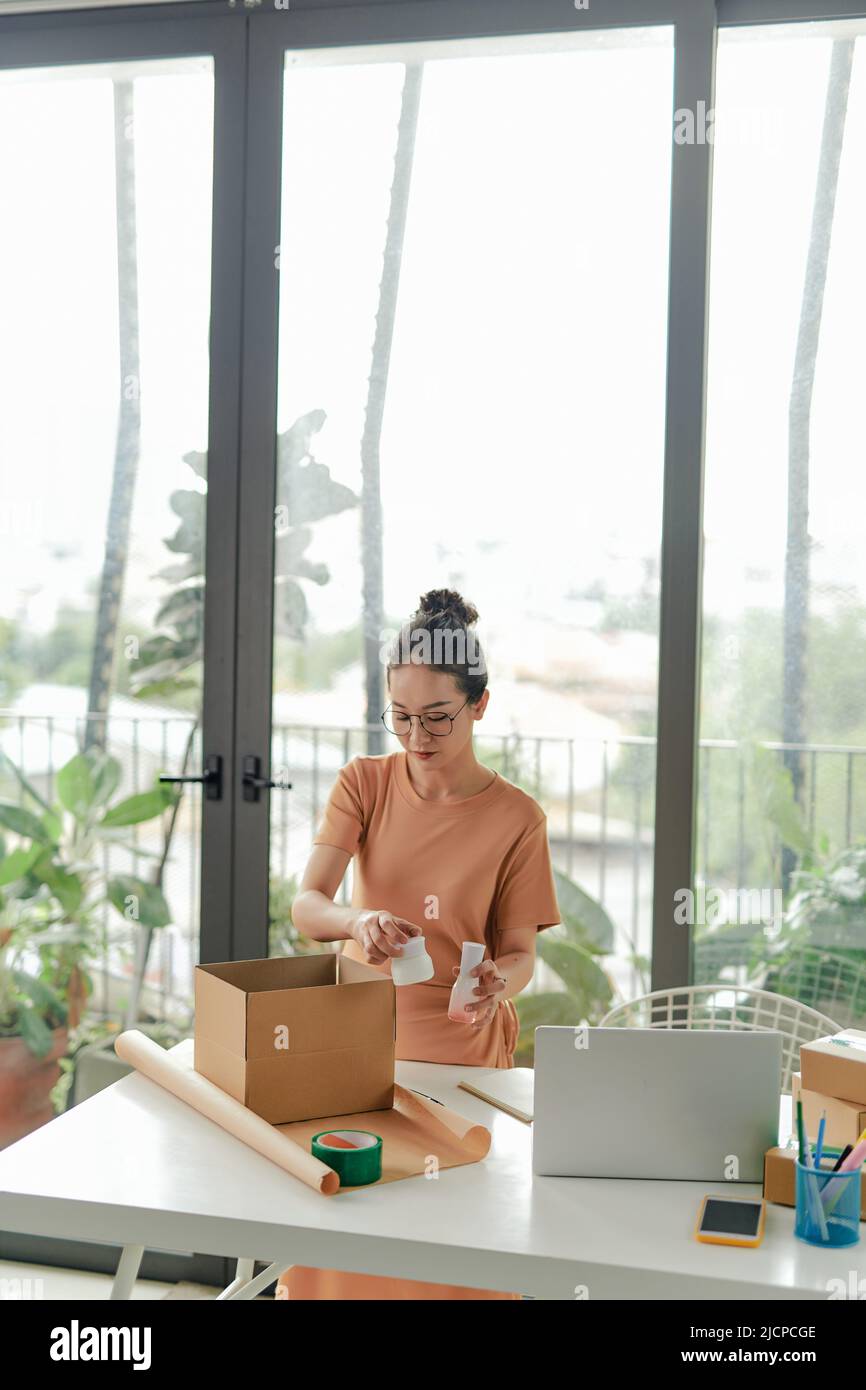 Young female packing product small business parcel order online retail store for delivery to customer. Stock Photo