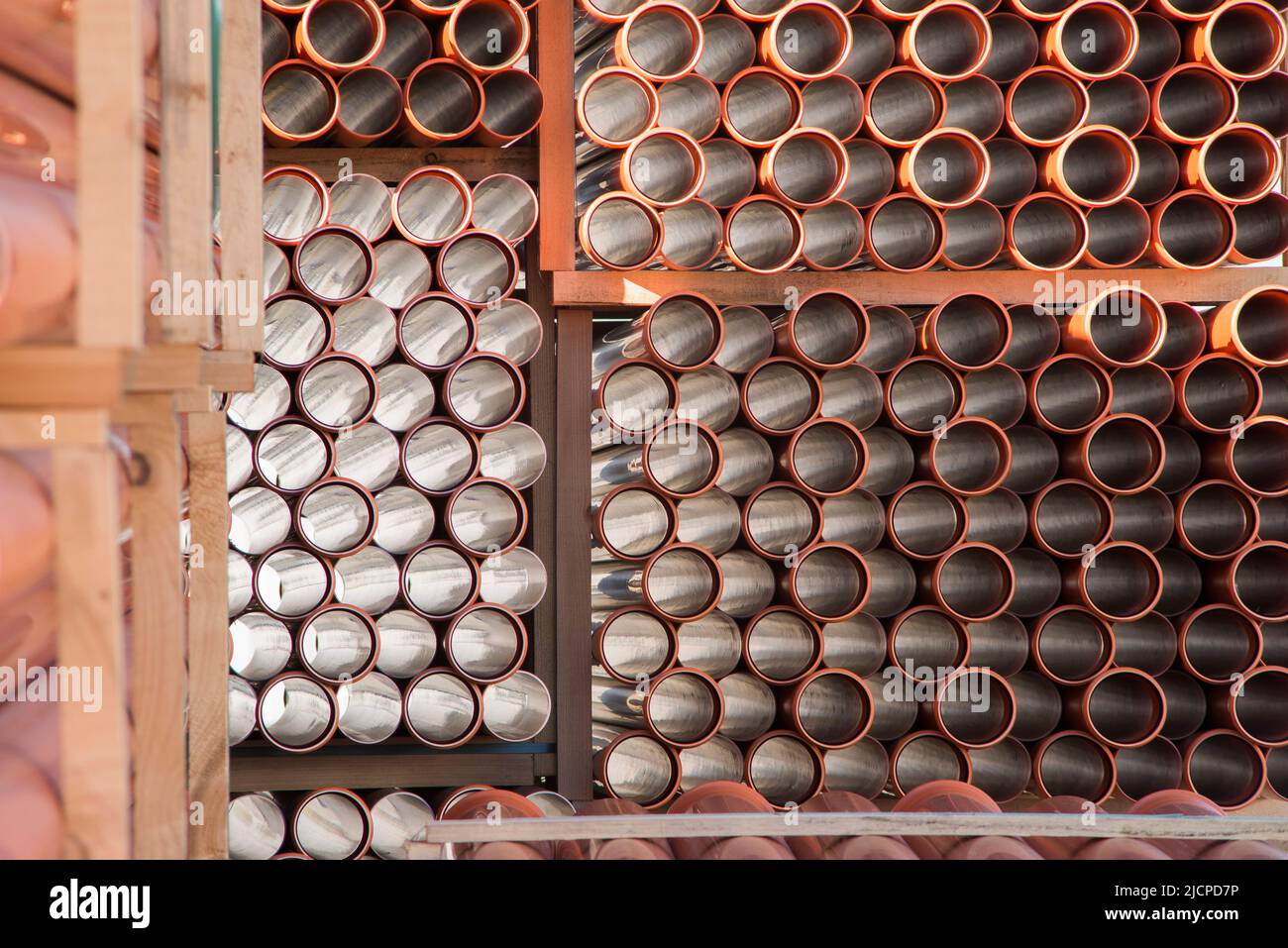 Background of orange plastic sewage pipes used at the building site. Texture and pattern of plastic drainage pipe. Light through tubes. Stock Photo