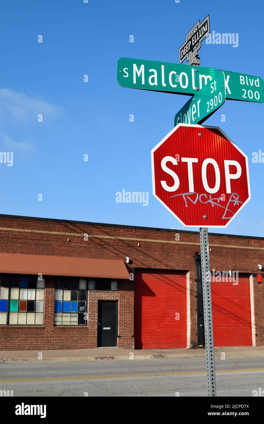 Stop sign on Malcolm X Blvd in Dallas, Texas, colorful brick building in the background ca. 2014 Stock Photo