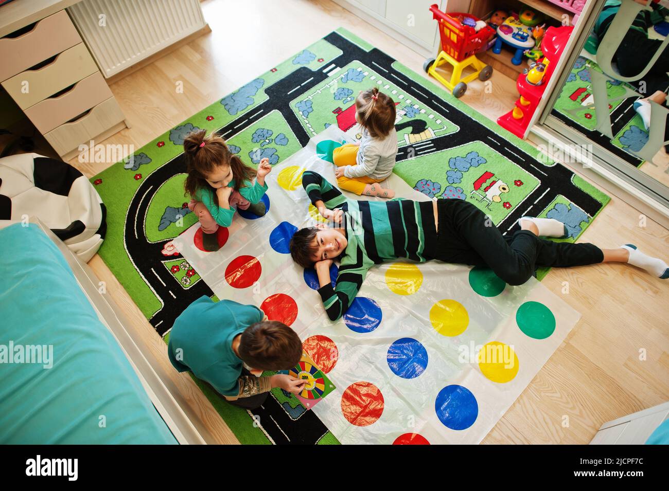 Happy family having fun together,four kids playing twister game at home. Stock Photo