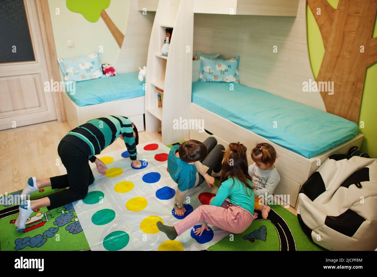 Happy family having fun together,four kids playing twister game at home. Stock Photo