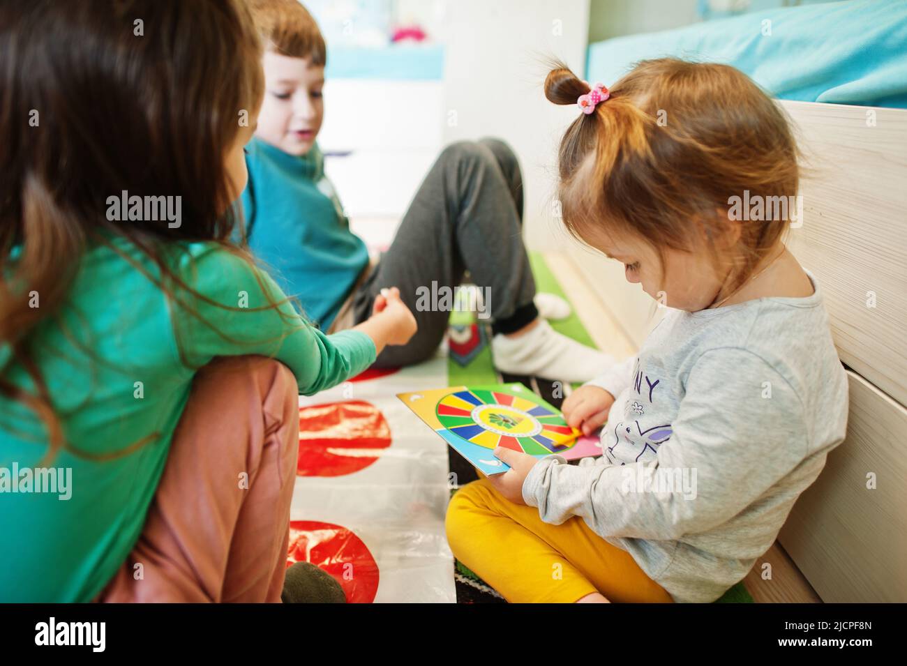Happy family having fun together,four kids playing twister game at home. Stock Photo