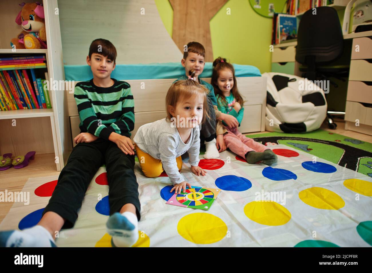 Happy family having fun together,four kids playing twister game at home. Stock Photo