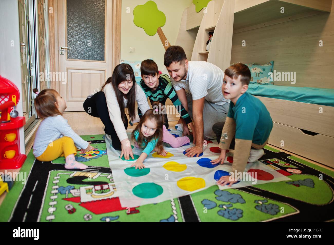 Happy big family having fun together,four kids playing twister game at home. Stock Photo