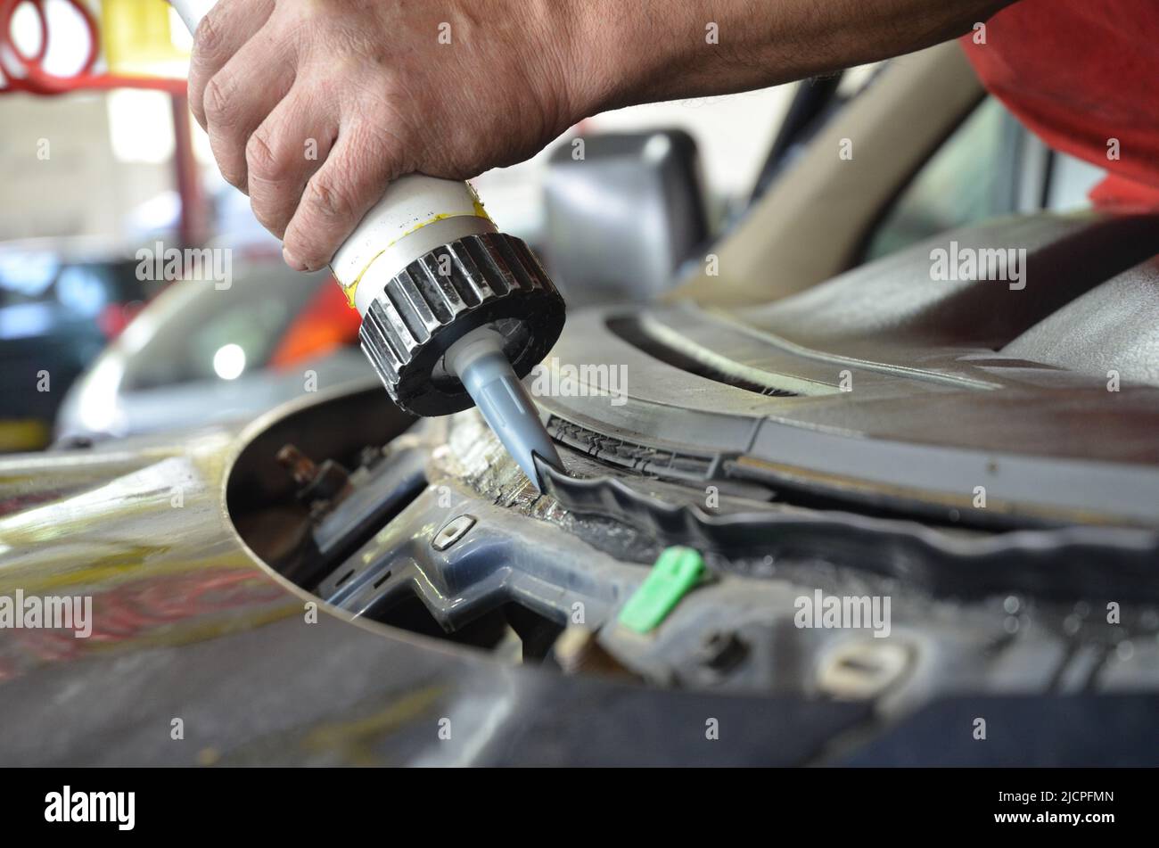 A car mechanic glues a broken windshield in a car repair shop Stock