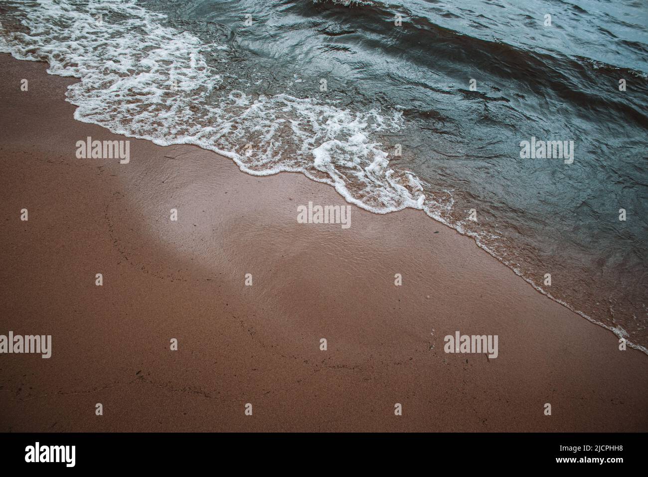 Waves washing onto sandy beach Stock Photo - Alamy