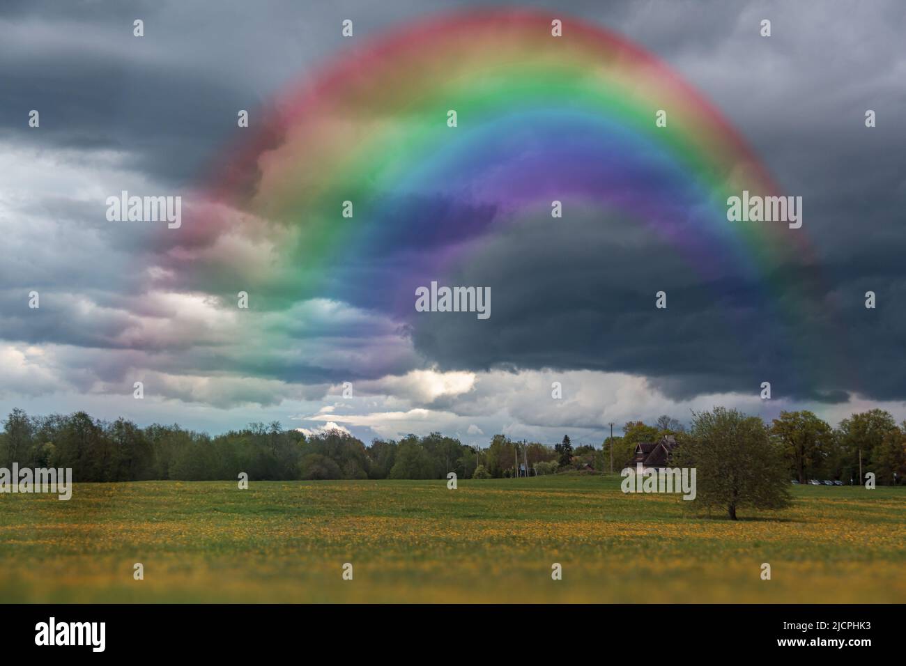 A rainbow in a dramatic sky with dark clouds. Rural landscape with ...