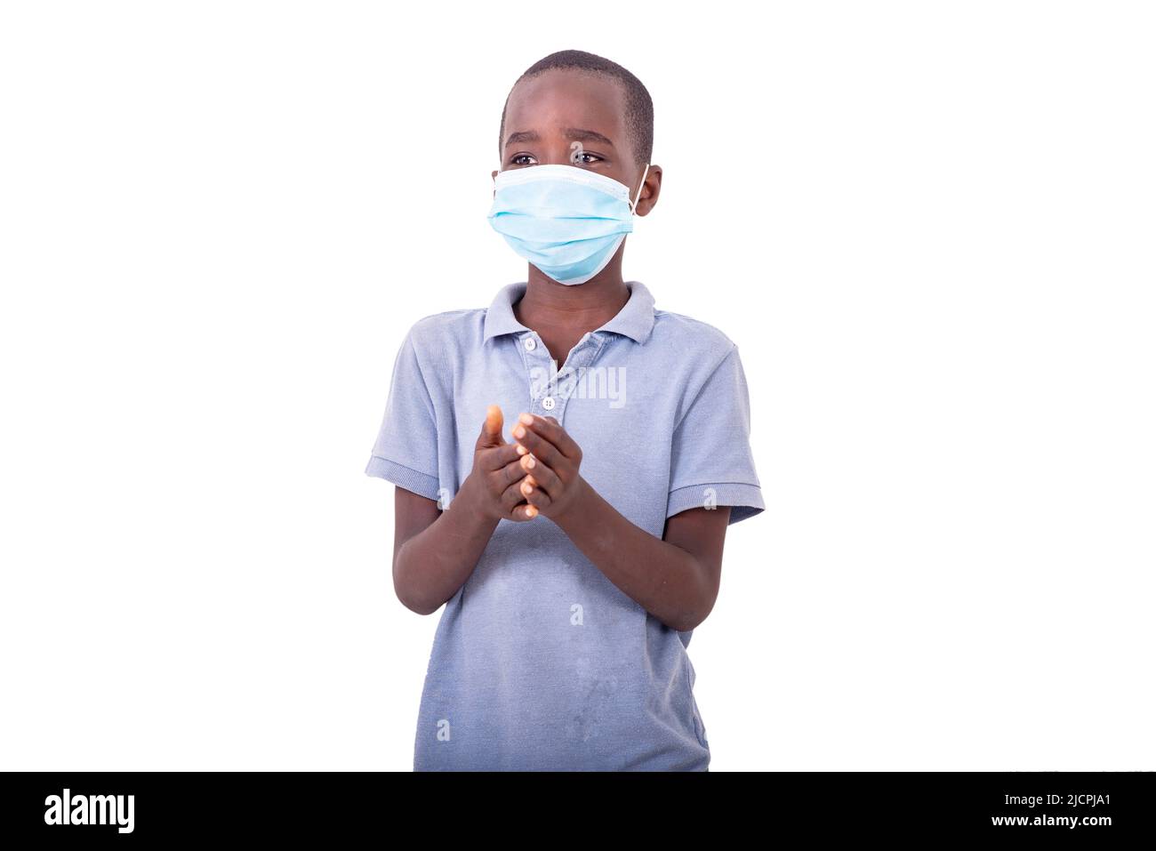 a little boy wearing a medical mask and holding hands together Stock ...