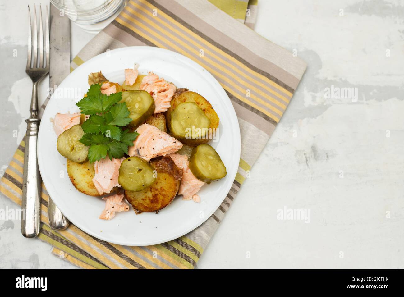 fresh baked salmon with fried potato and cucumber on white plate Stock Photo