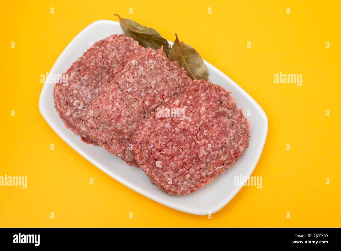 fresh raw minced meat on white dish with bay leaf Stock Photo