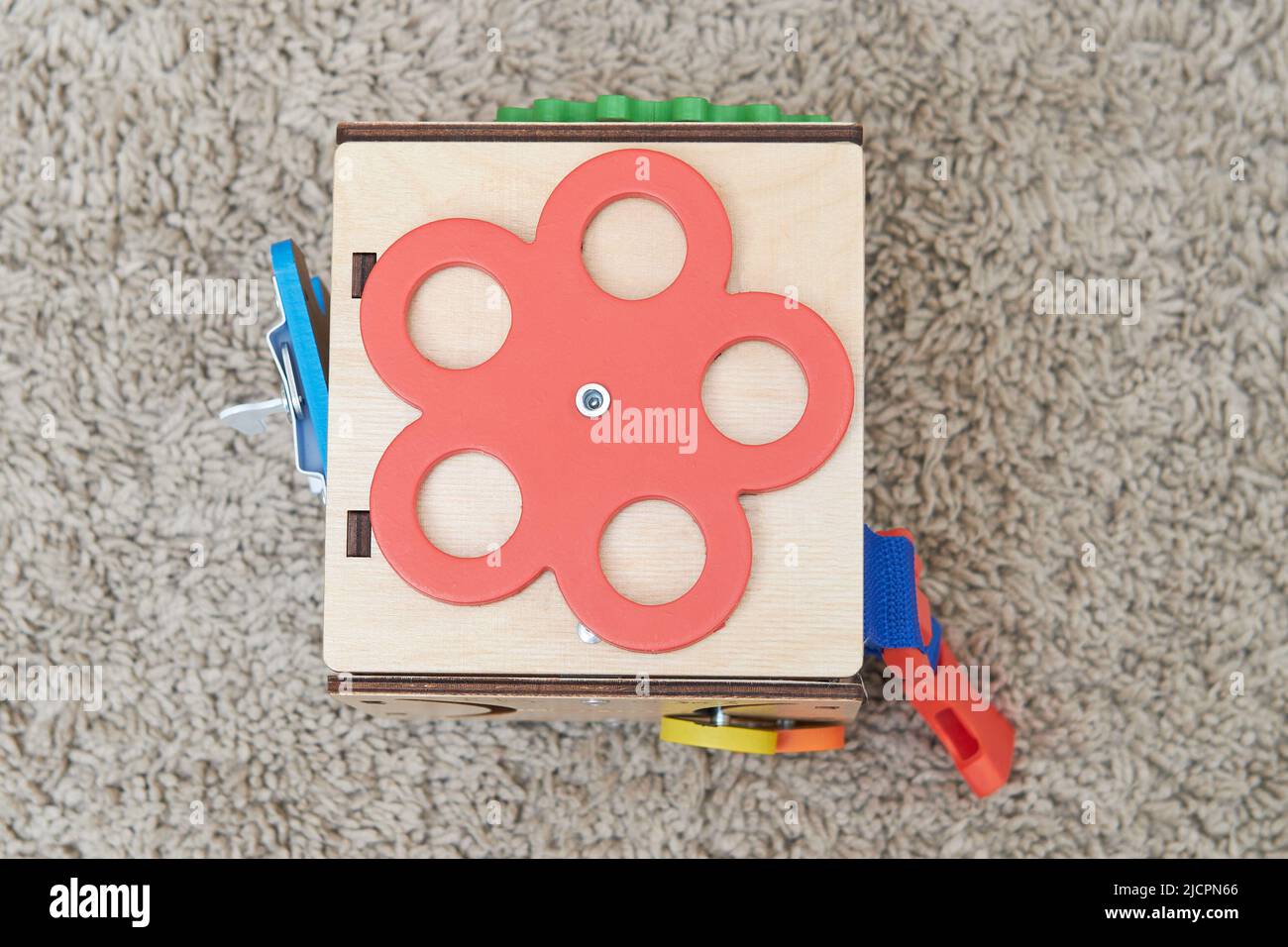 Busyboard cube for infant baby on the nursery floor. Educational toys for children, wooden gamepanel Stock Photo