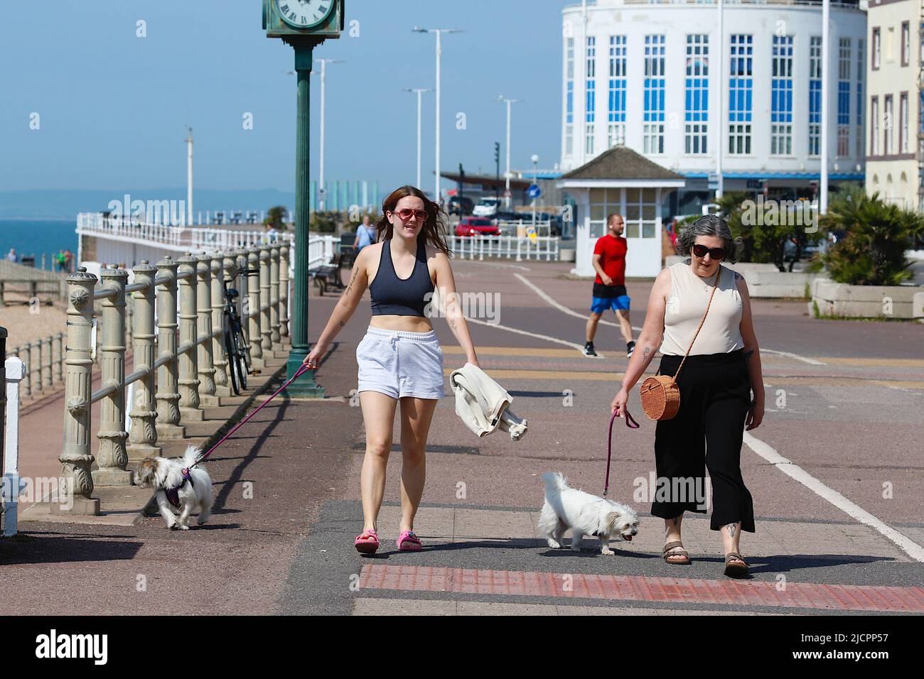 Hastings, East Sussex, UK. 15 Jun, 2022. UK Weather: Hot and sunny at the seaside town of Hastings in East Sussex as Brits enjoy the warm weather today along the seafront promenade. Two woman enjoying the sunshine while walking their dogs. Photo Credit: Paul Lawrenson /Alamy Live News Stock Photo