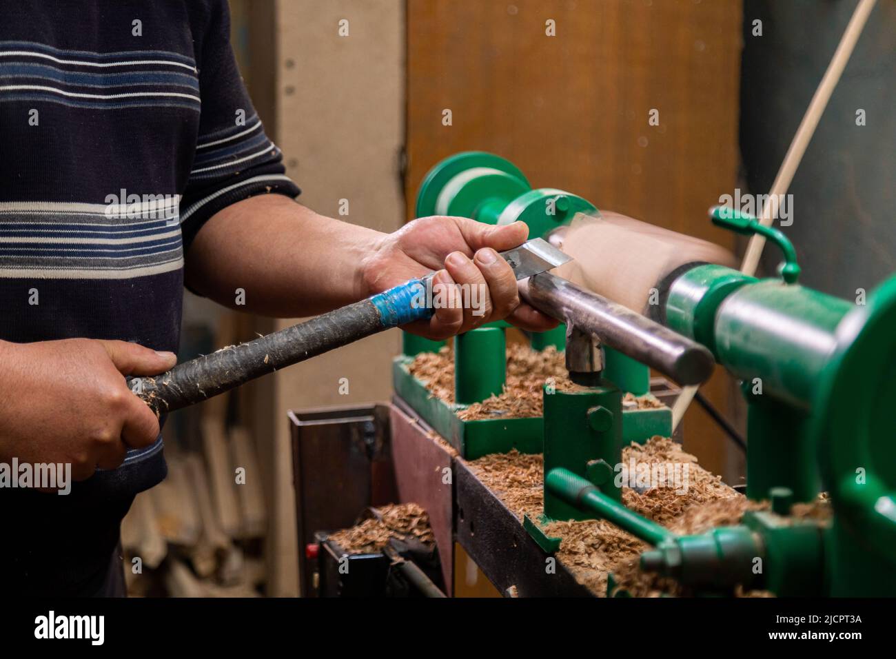Closeup of carpenter turning wood on a lathe. Person carving chisel candlestick on a lathe Stock