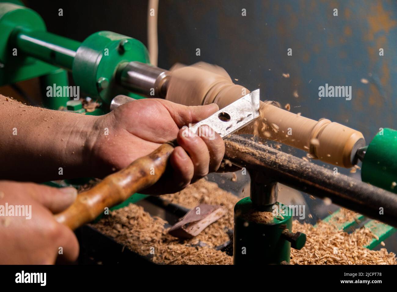 Closeup of carpenter turning wood on a lathe. Person carving chisel candlestick on a lathe Stock
