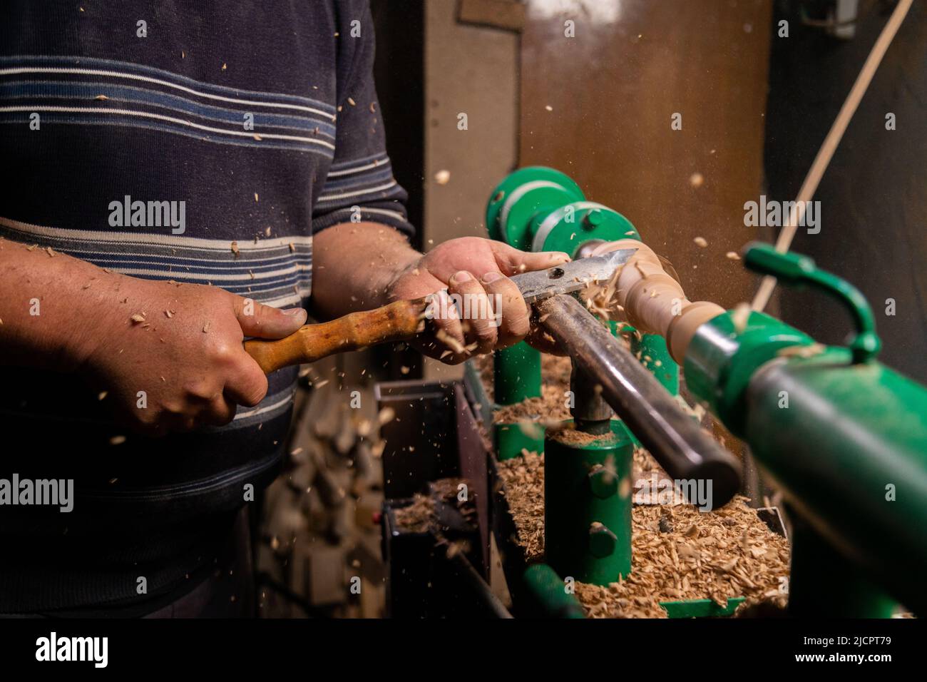 Closeup of carpenter turning wood on a lathe. Person carving chisel candlestick on a lathe Stock