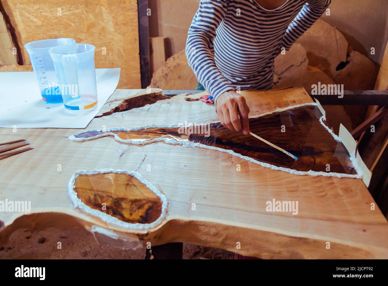 Carpenter removing air bubbles from epoxy table. Process of making a