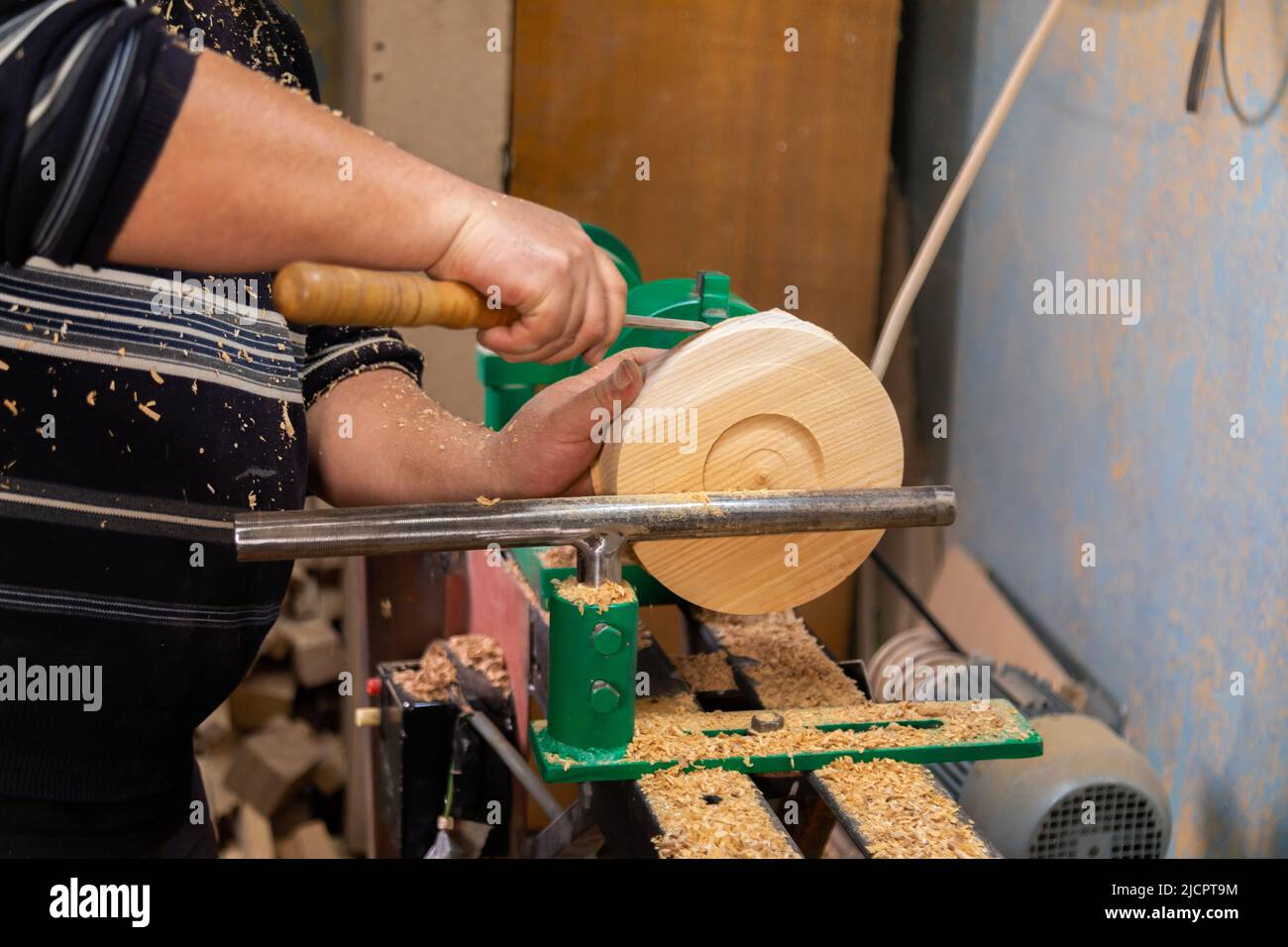 Closeup of carpenter turning wood on a lathe. Person carving chisel candlestick on a lathe Stock