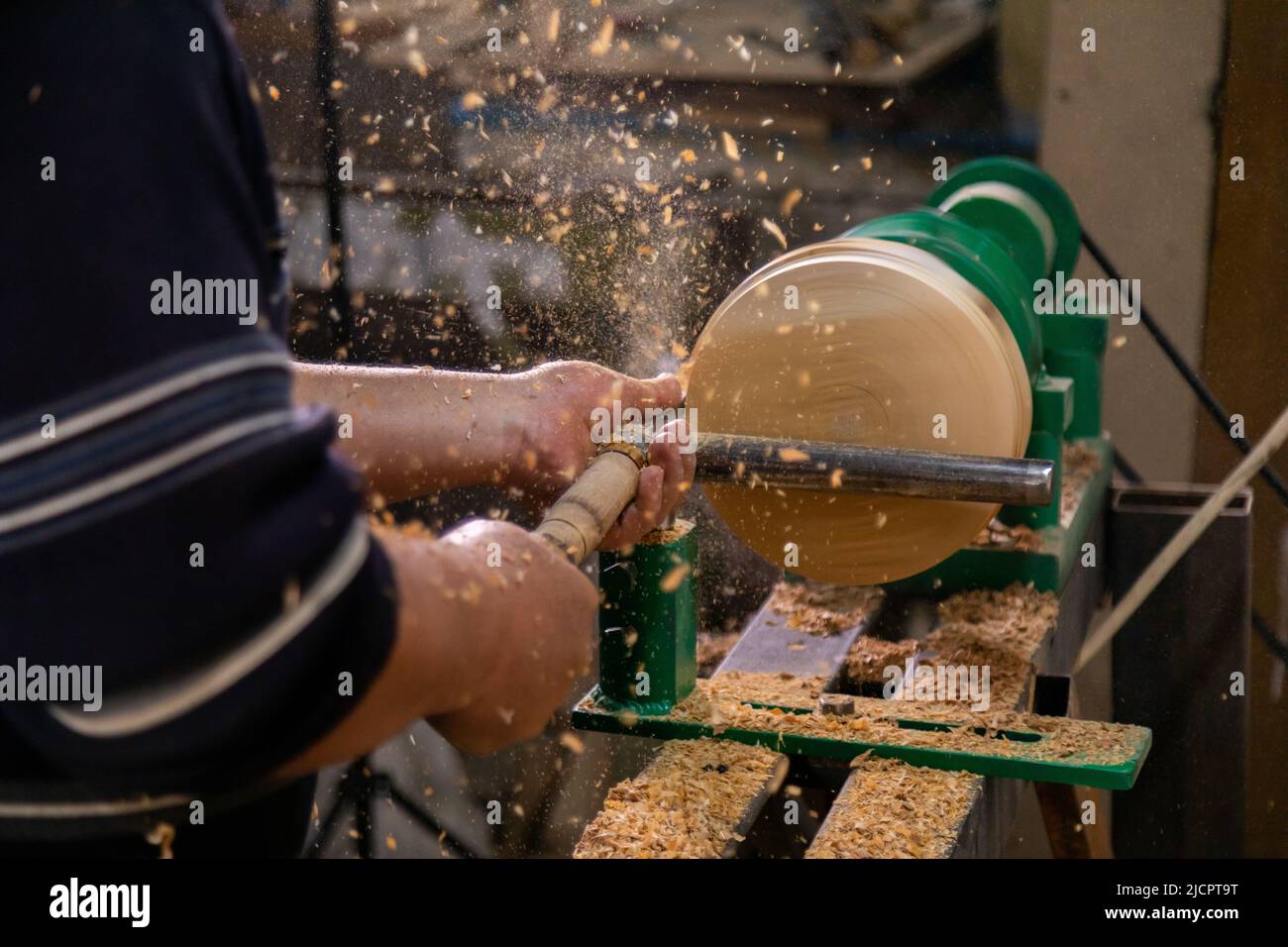 Closeup of carpenter turning wood on a lathe. Person carving chisel candlestick on a lathe Stock