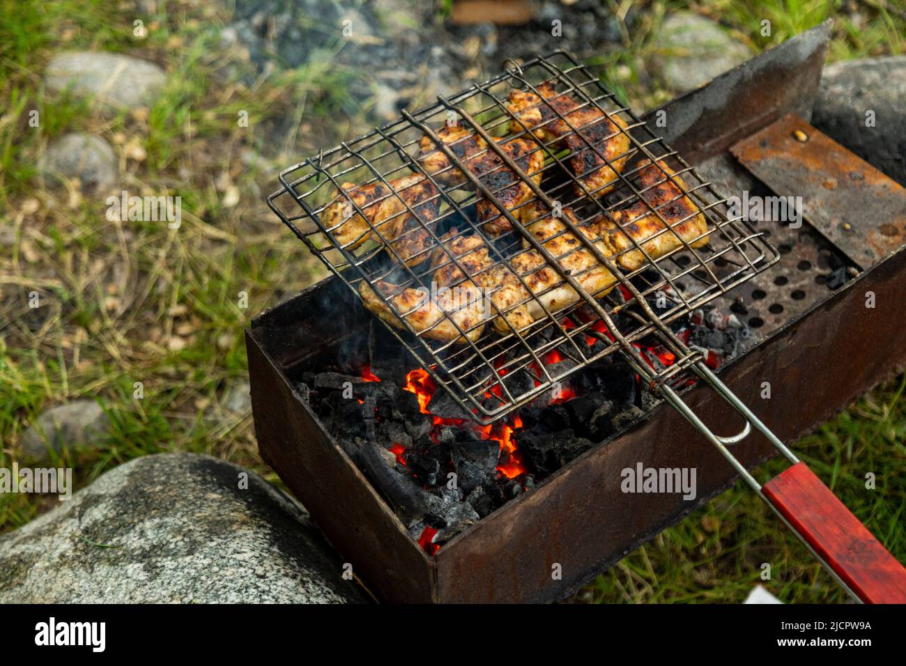 Chicken wings in metal grate grilling on a brazier with flaming