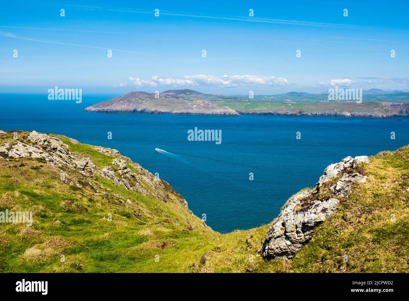 View across calm blue sea to Llyn Peninsula from Mynydd Enlli mountain on Ynys Enlli or Bardsey Island on Welsh west coast.  Gwynedd, north Wales, UK Stock Photo