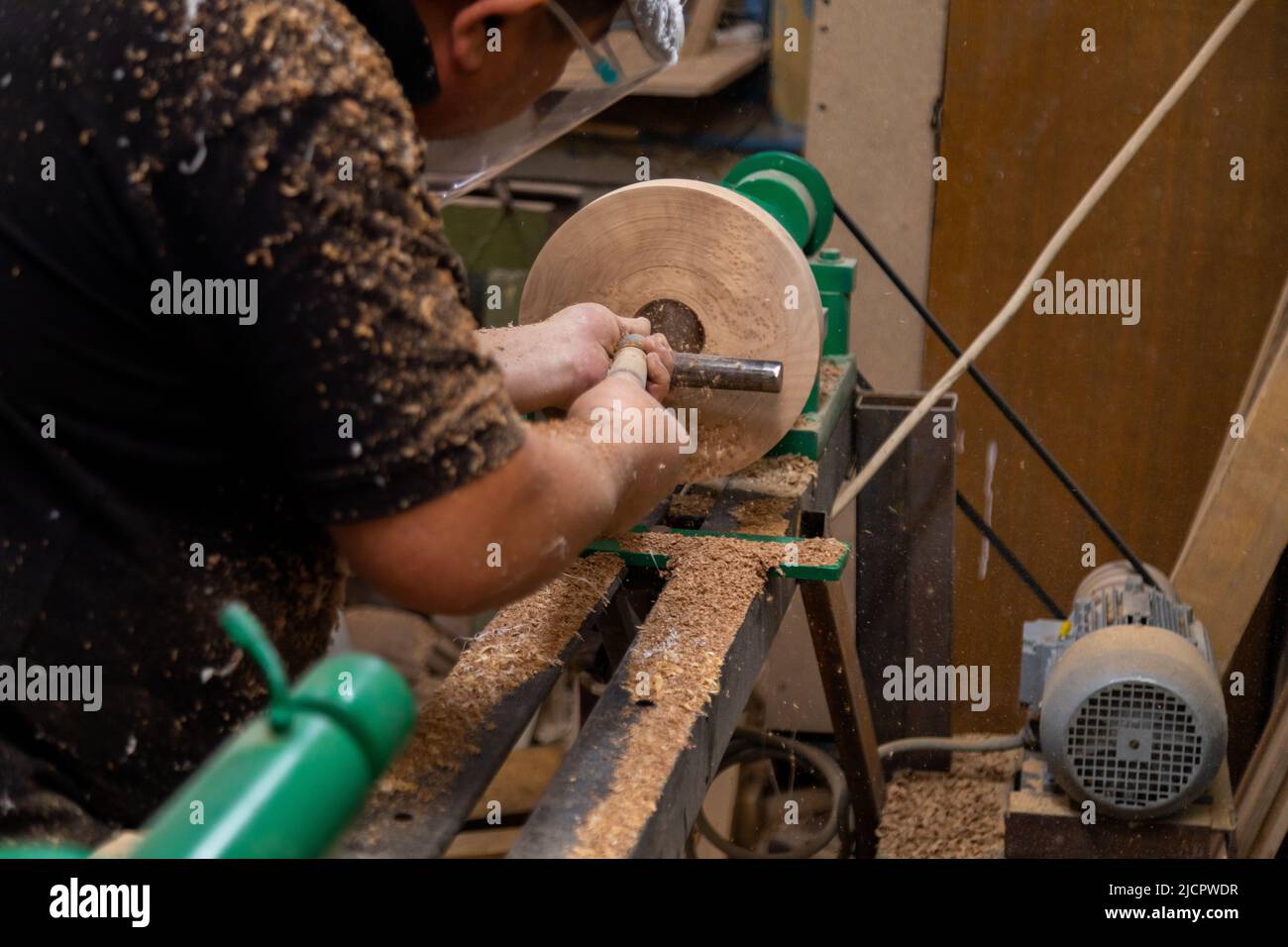 Closeup of carpenter turning wood on a lathe. Person carving chisel candlestick on a lathe Stock