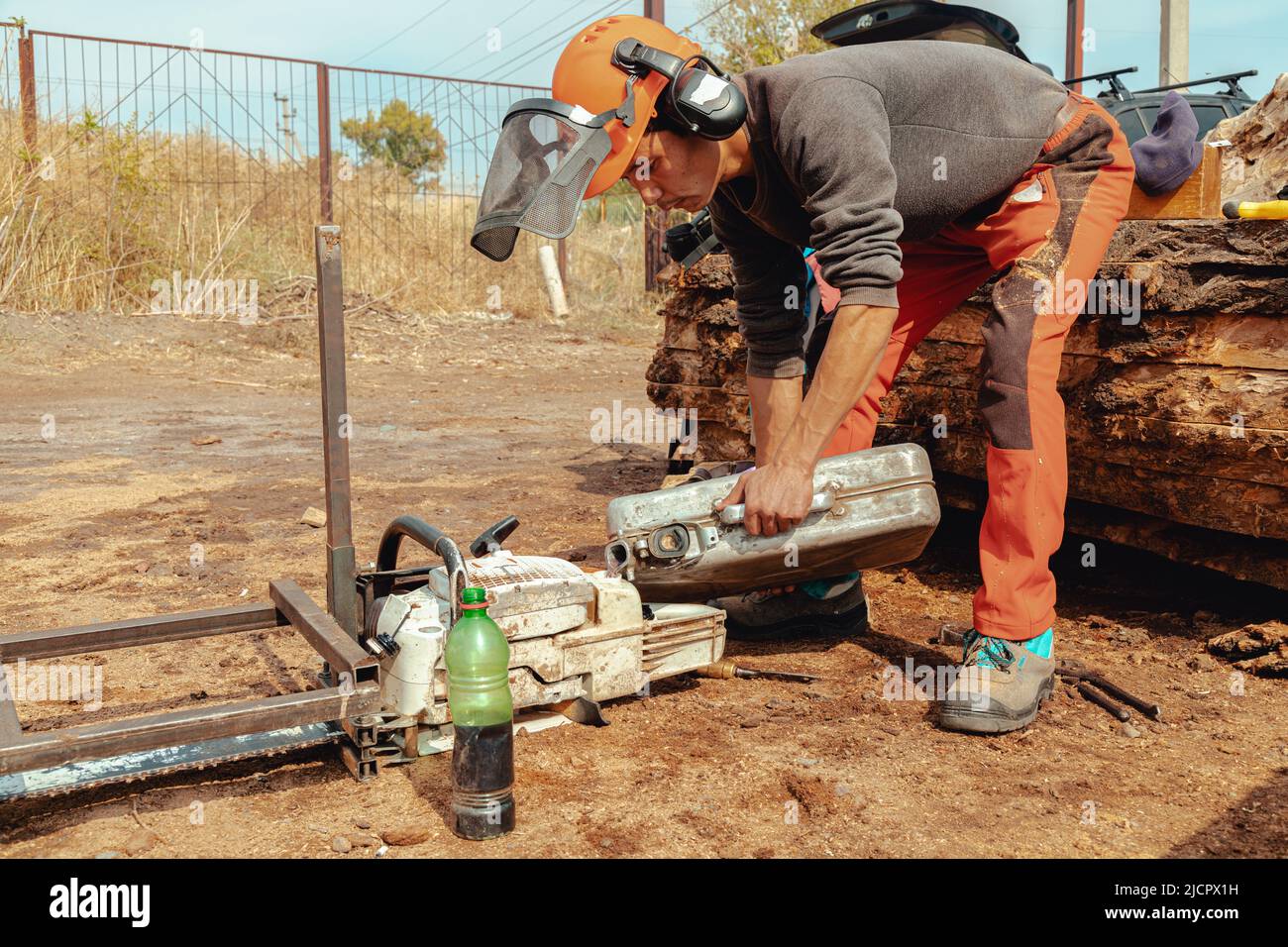 Lumberjack pouring gas to oil mixture into the chainsaw fuel tank Stock