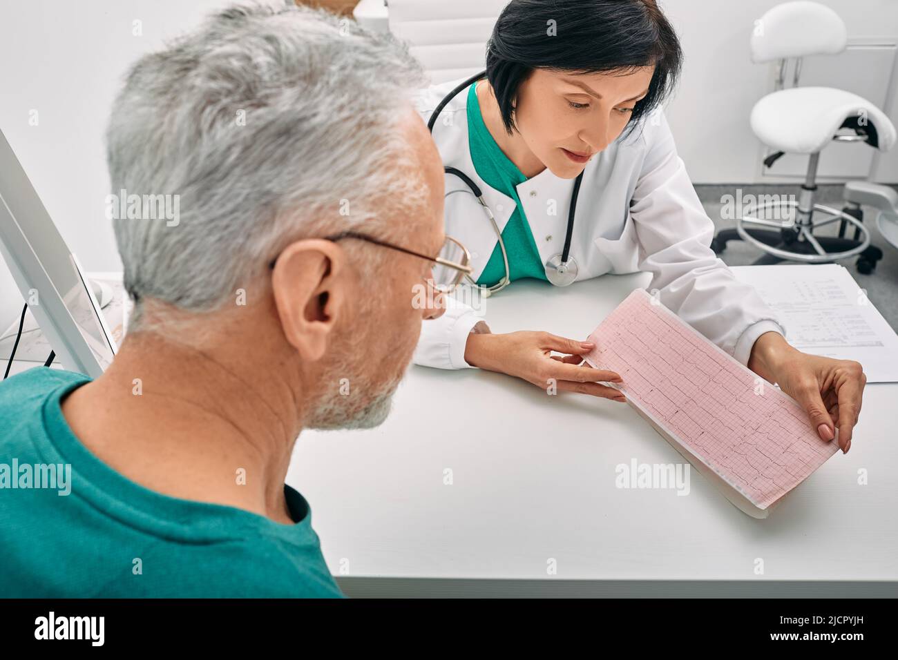 Experienced doctor consulting senior man on results of cardiogram and test. Diagnostic heart diseases, cardiology Stock Photo
