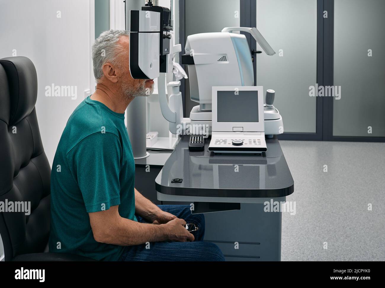 Senior man has eye test in ophthalmological clinic using phoropter. Eye test, vision diagnostic Stock Photo