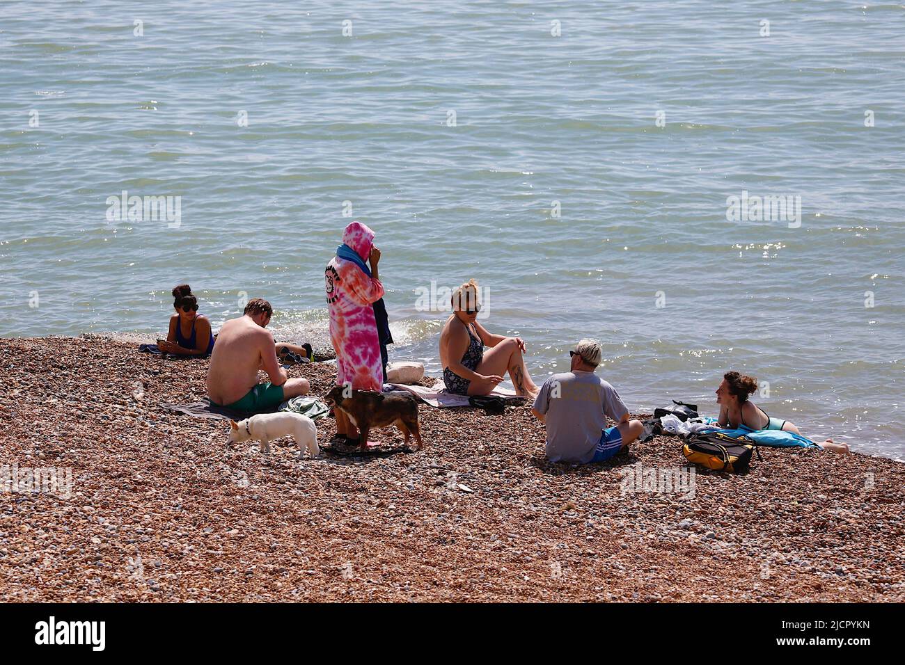 Hastings, East Sussex, UK. 15 Jun, 2022. UK Weather: Hot and sunny at the seaside town of Hastings in East Sussex as Brits enjoy the warm weather today along the seafront promenade. A family sits by the edge of the sea lapping up the gentle waves. Photo Credit: Paul Lawrenson /Alamy Live News Stock Photo