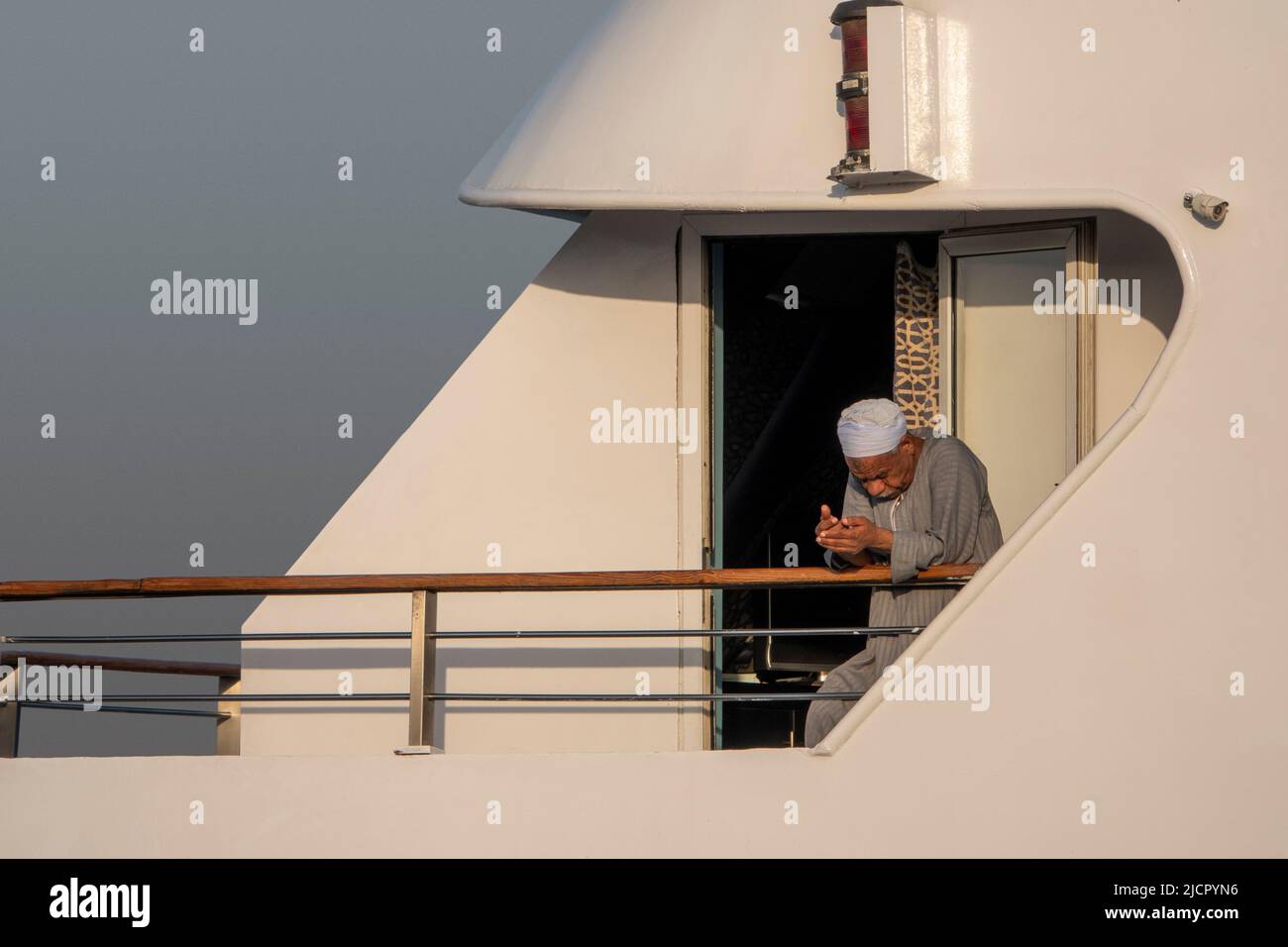 Nile boat captain takes time out for contemplation leaning on cruise boat handrail Stock Photo