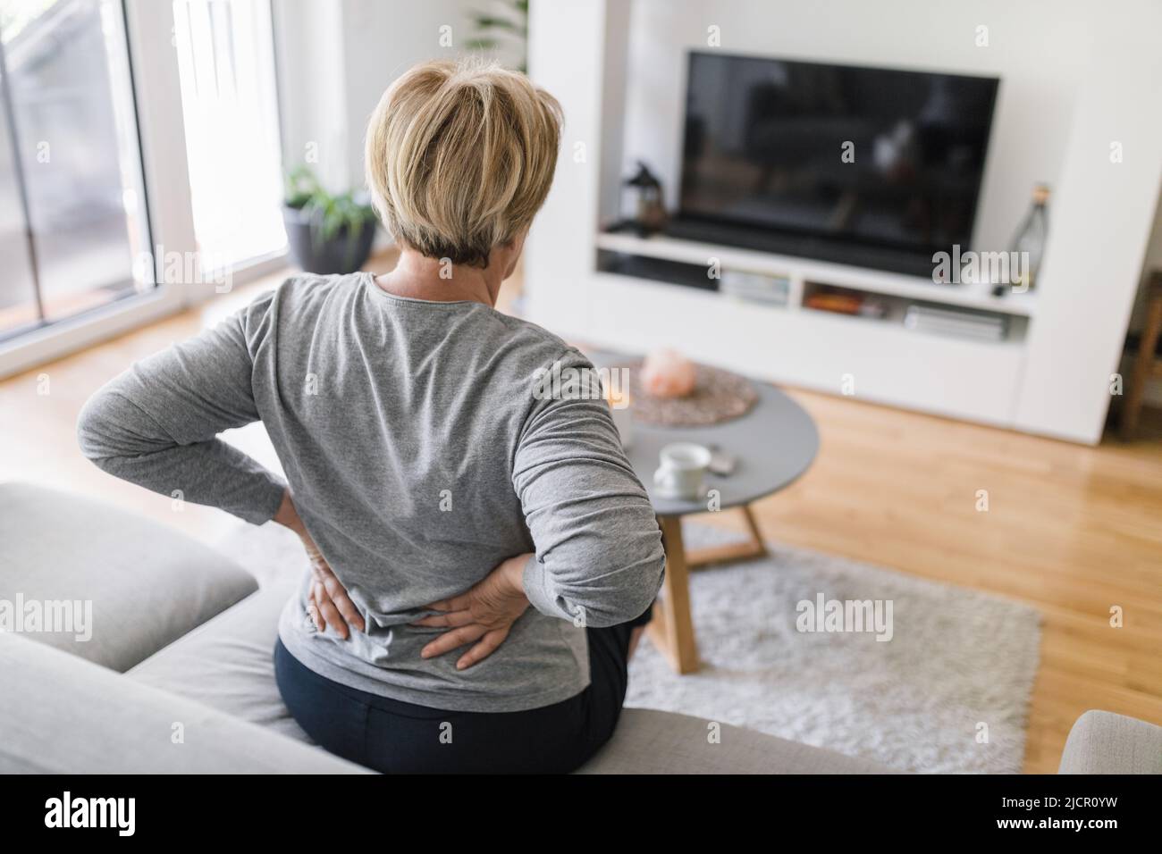 Elderly woman at home with lower back pain Stock Photo