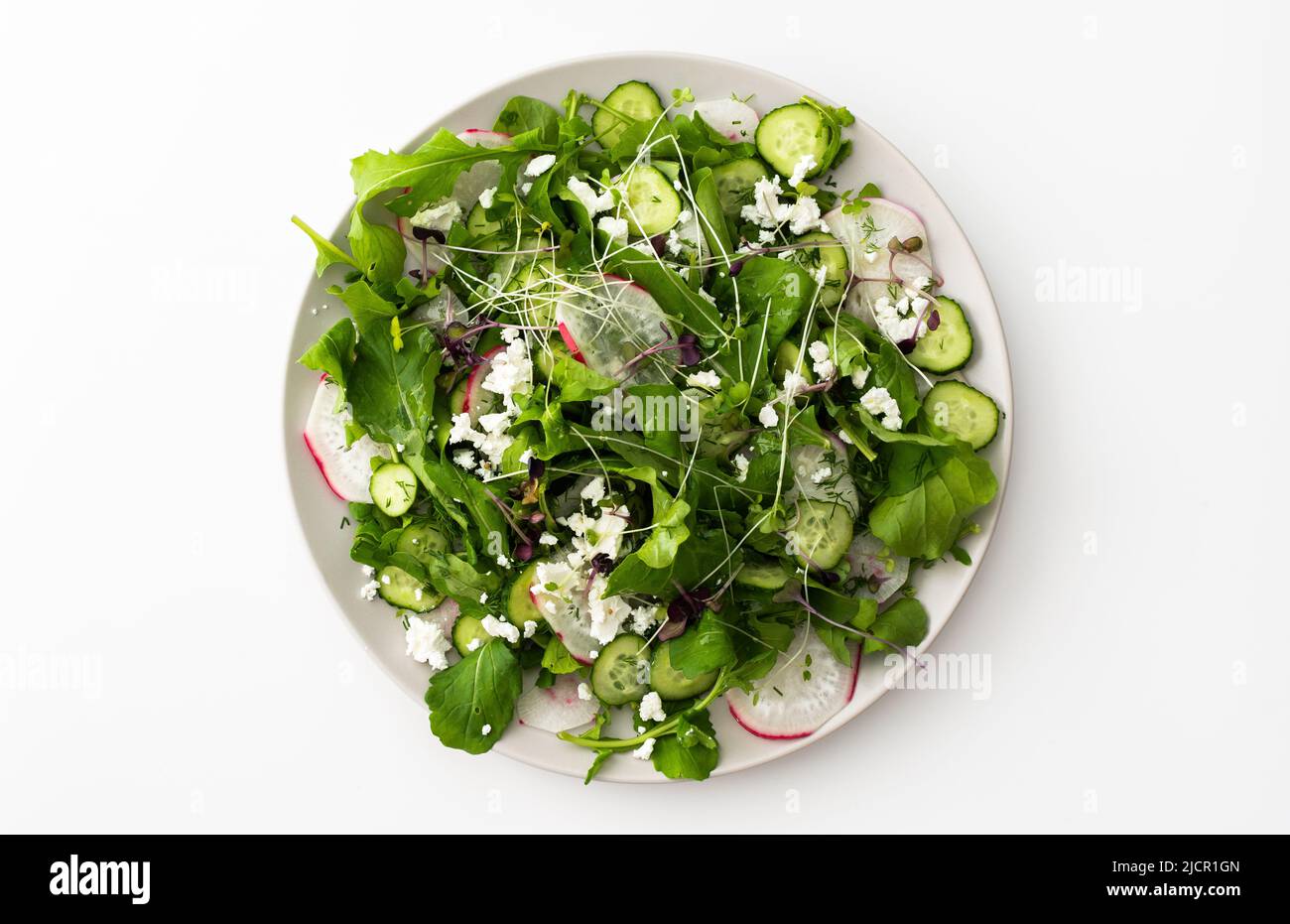 Delicious light salad with cucumbers and arugula, feta and microgreens, radishes and dill Stock Photo