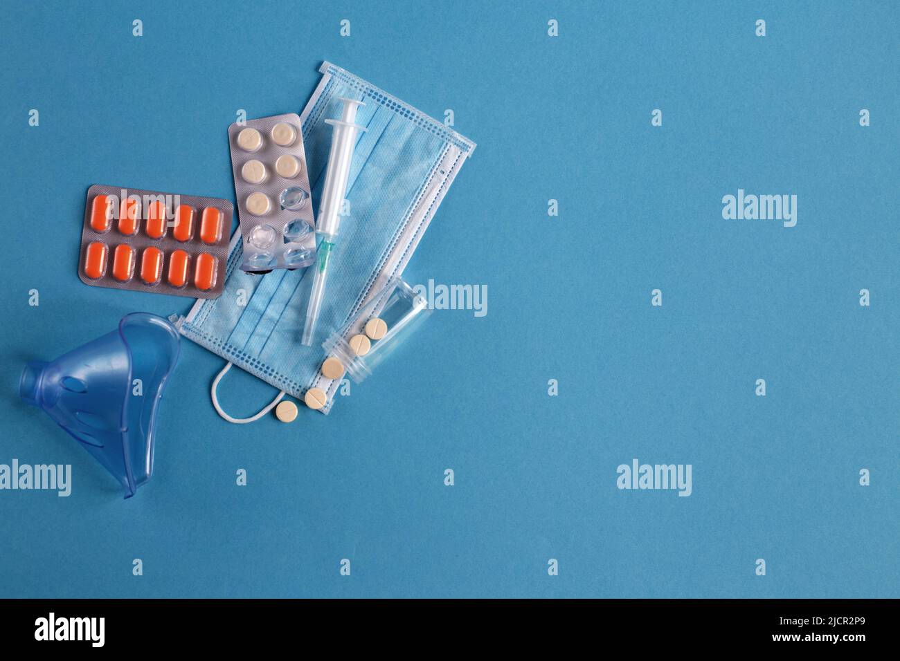 medical mask, syringe and tablets close on the blue background. Coronavirus, flu, respiratory disease concept. Horizontal orientation. Top view. Stock Photo