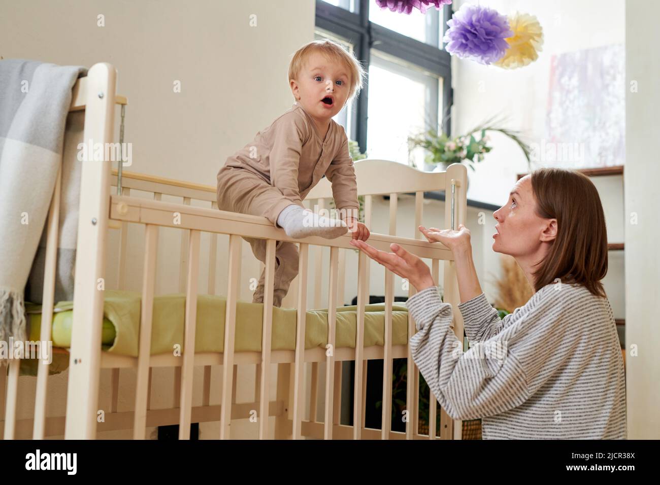 Little child waking up in the morning and climbing out of his crib with