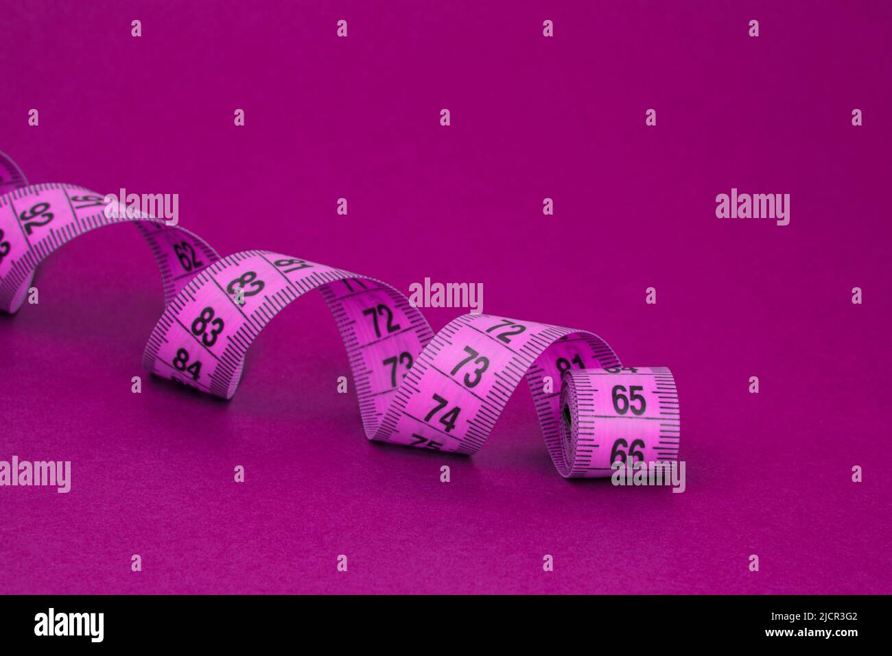 Colorful pink tape measure spiral with copyspace background Stock Photo