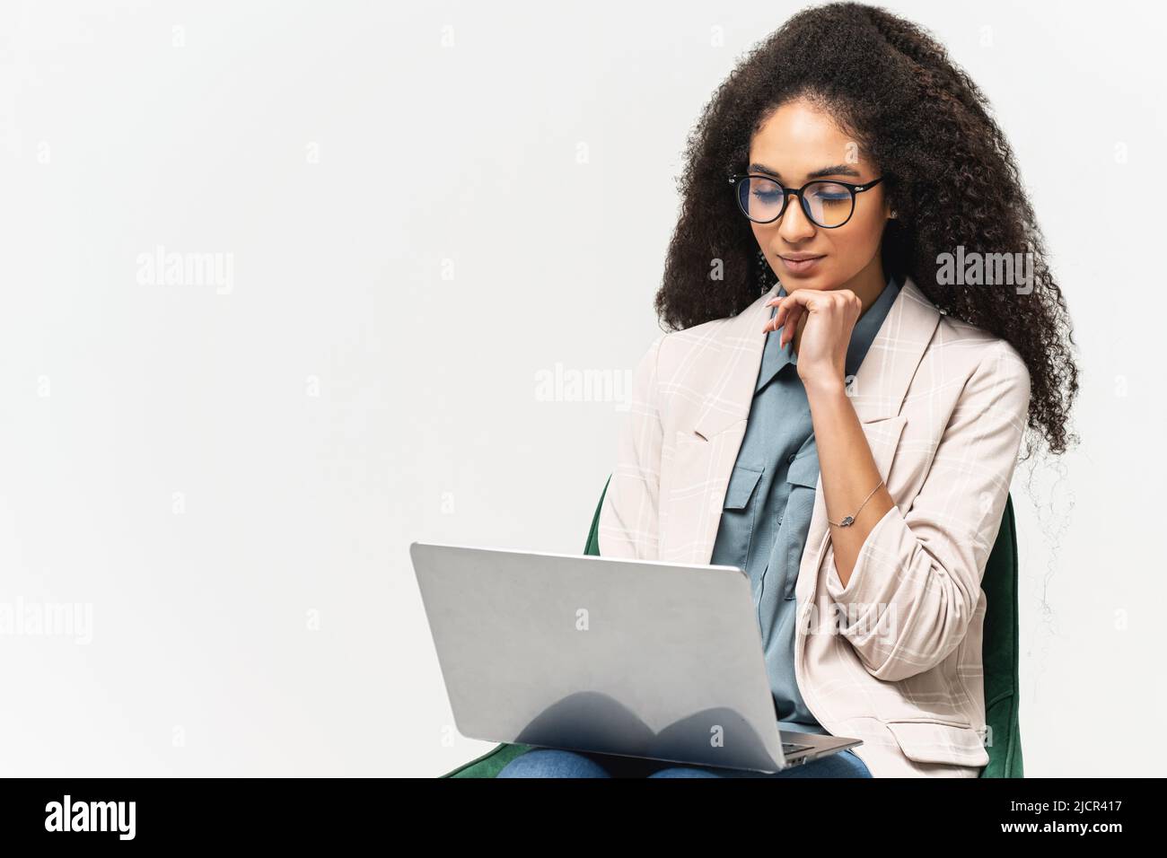 Smart and confident African-American woman in smart wear using laptop isolated on white background, female office employee or student typing, web browsing Stock Photo