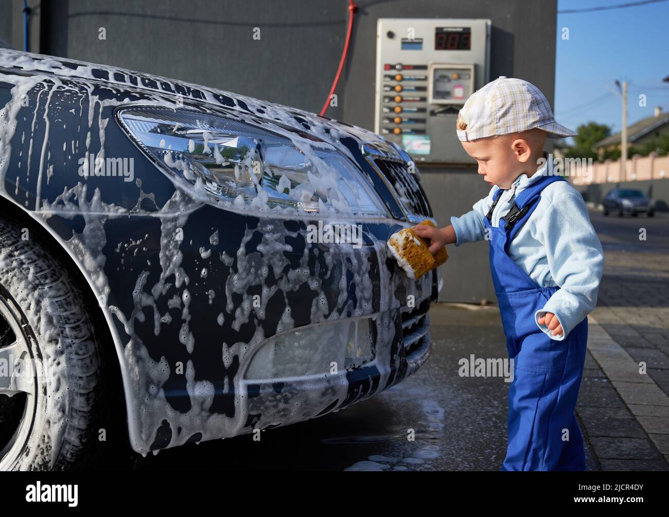 Kid car washer who carefully examining process of hand cleaning machine