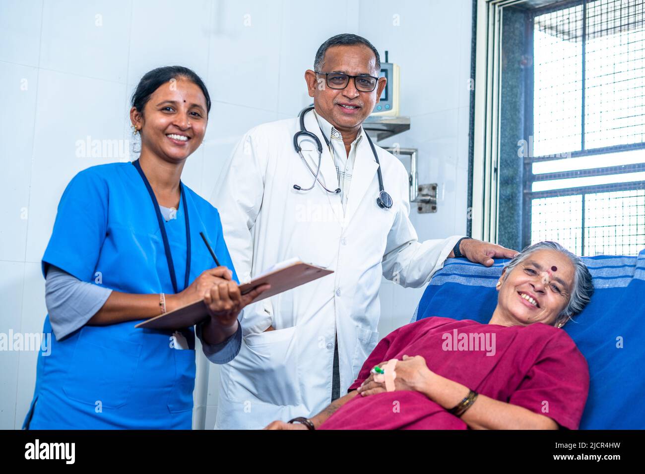 Happy smiling doctor, patient and nurse looking at camera during ward visit at hospital - concept of recovery, medicare and treatment. Stock Photo