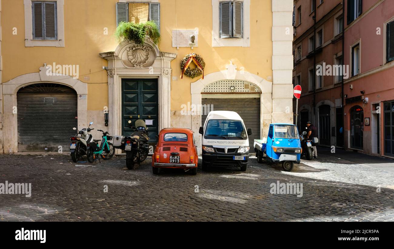 Rome, Italy - June 6, 2022: Vehicles of contrasting type and color at rest on cobbled street in Rome, Italy. Stock Photo