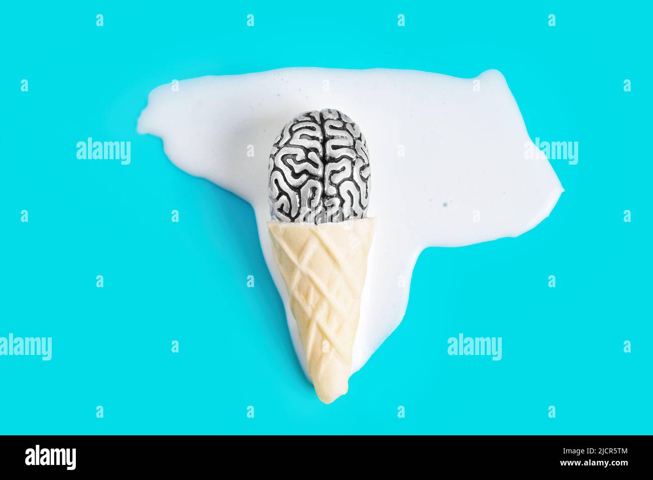 Icing Brain Human brain anatomical copy placed in a melted ice cream on a blue ...