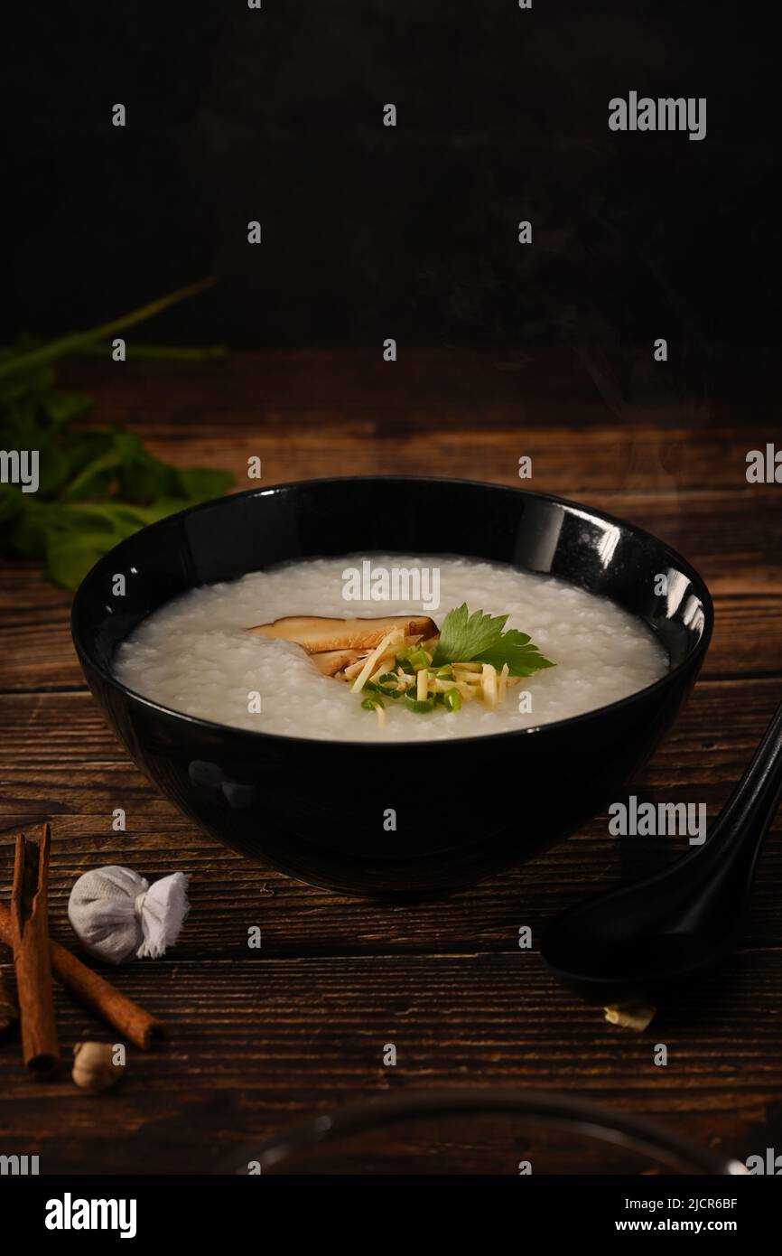 Traditional Chinese porridge rice in bowl with soft boiled egg, shiitake mushroom, slice ginger and slice scallion. Stock Photo