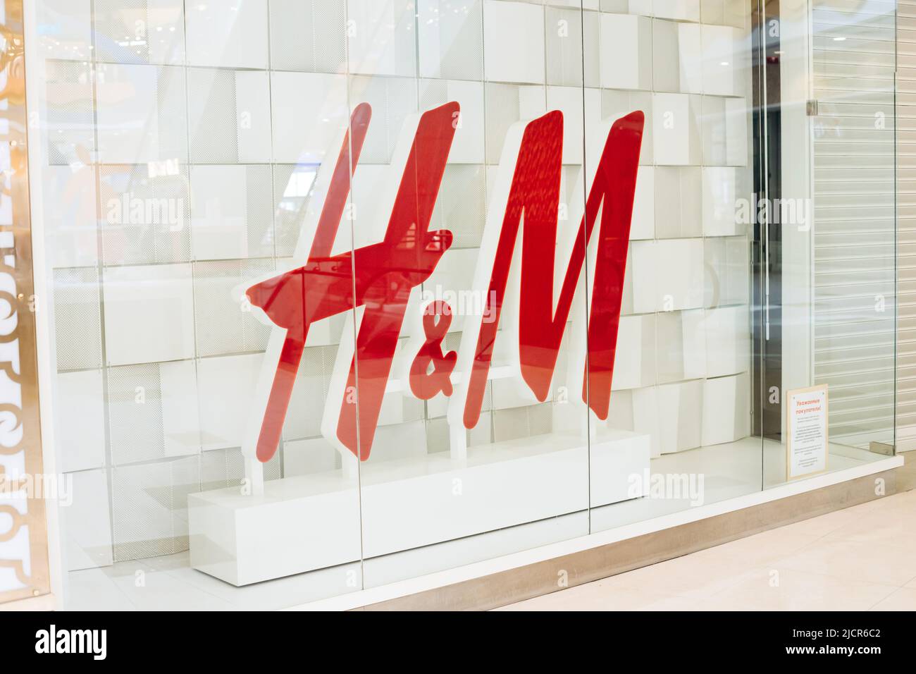 Saint Petersburg, Russia - 04.01.2022: Big logo of Hennes and Mauritz or hm or H and M in showcase or shop window. Close-up. Stock Photo