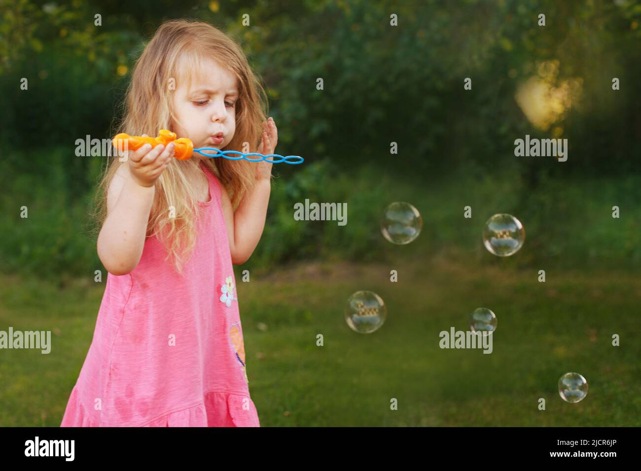 Cute little girl is blowing a soap bubbles Stock Photo - Alamy