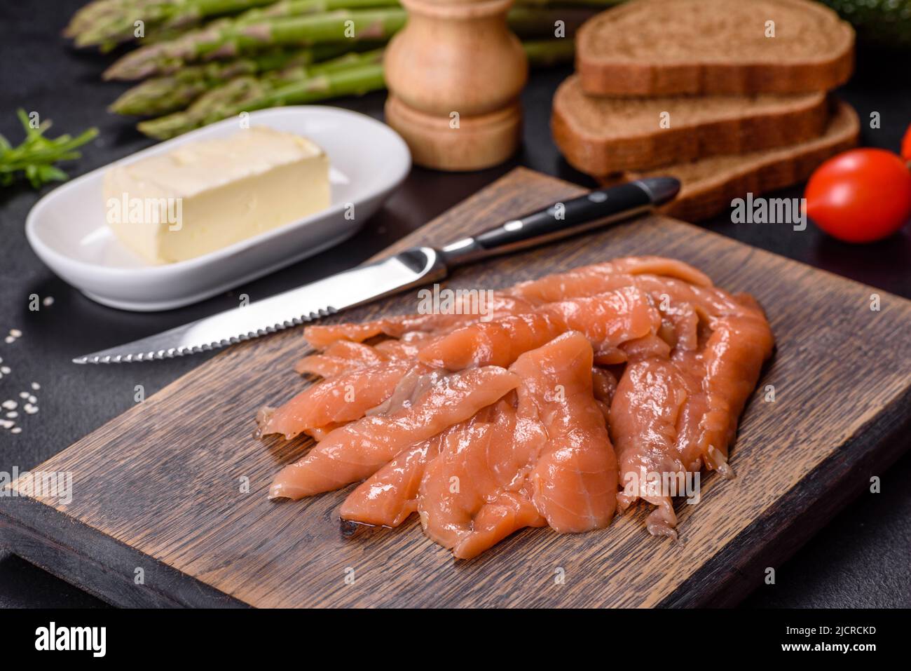 Beautiful delicious red fish slices on a wooden cutting board against a dark concrete background Stock Photo