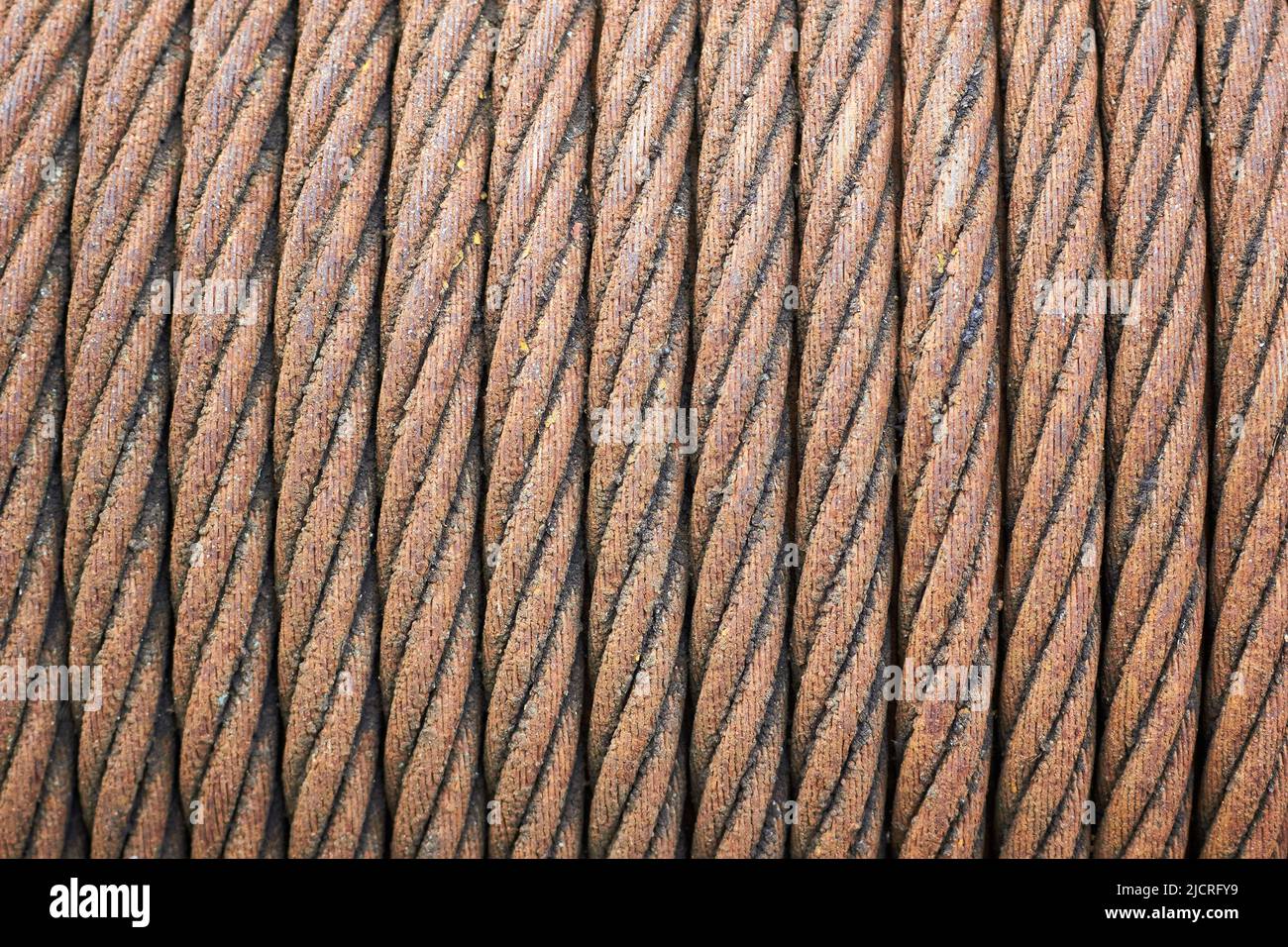 Steel cable sling hoist. Old obsolete rusty steel braided cable wounded on drum of industrial winch selective focuse macro closeup texture background. Stock Photo