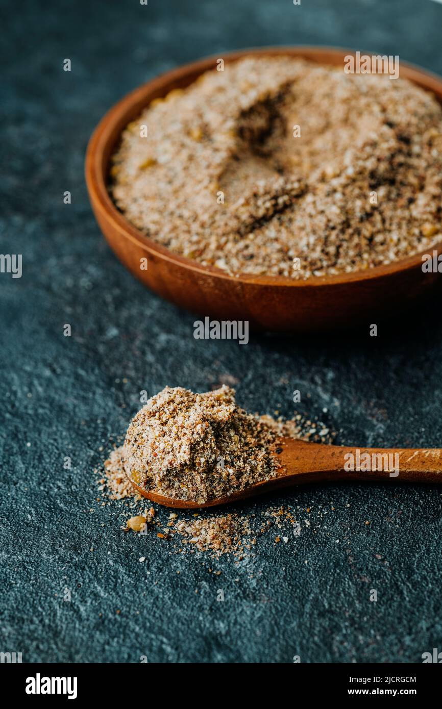 closeup of a wooden bowl and a wooden spoon with some vegan breakfast instant mix, made with acai,  strawberry and banana, on a gray stone surface Stock Photo