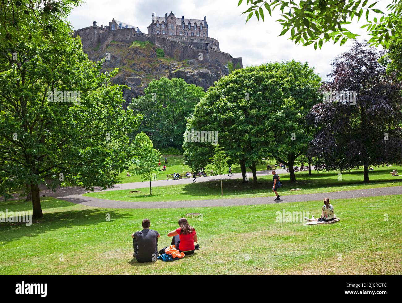 Edinburgh city centre, Scotland, UK. 15.06.2022. Summer arrives in the city after a recent cool cloudy period of weather. Mid-afternoon temperature of 18 degrees centigrade encouraging people out into the city's green spaces. Pictured: People relax in the sunshine in Princes Street Gardens West under the shadow of Edinburgh Castle Credit: Scottishcreative/alamy live news. Stock Photo