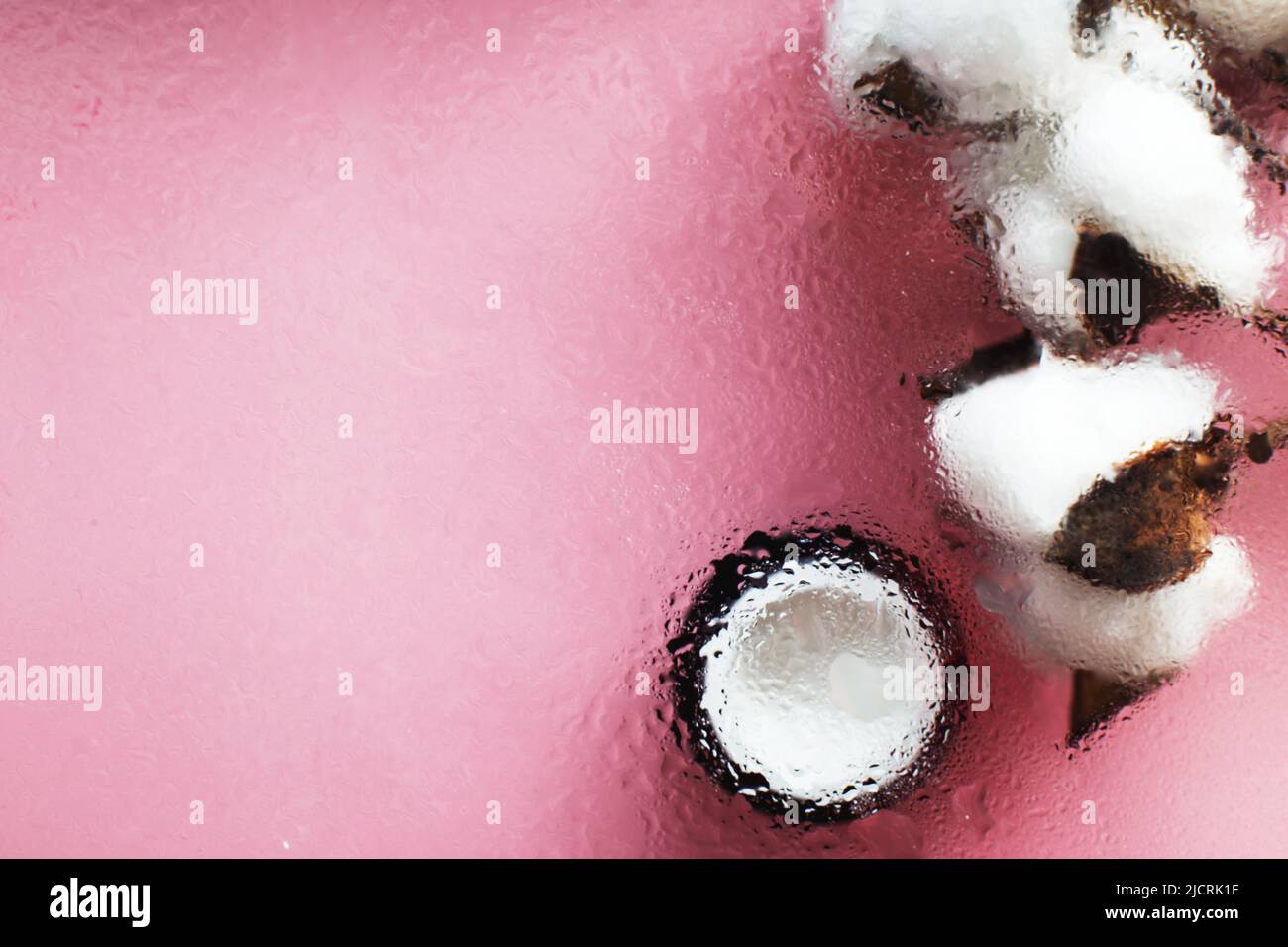 Concept of natural moisturizing skin care products. Face and hand cream under a glass surface with water on a pink background. Stock Photo