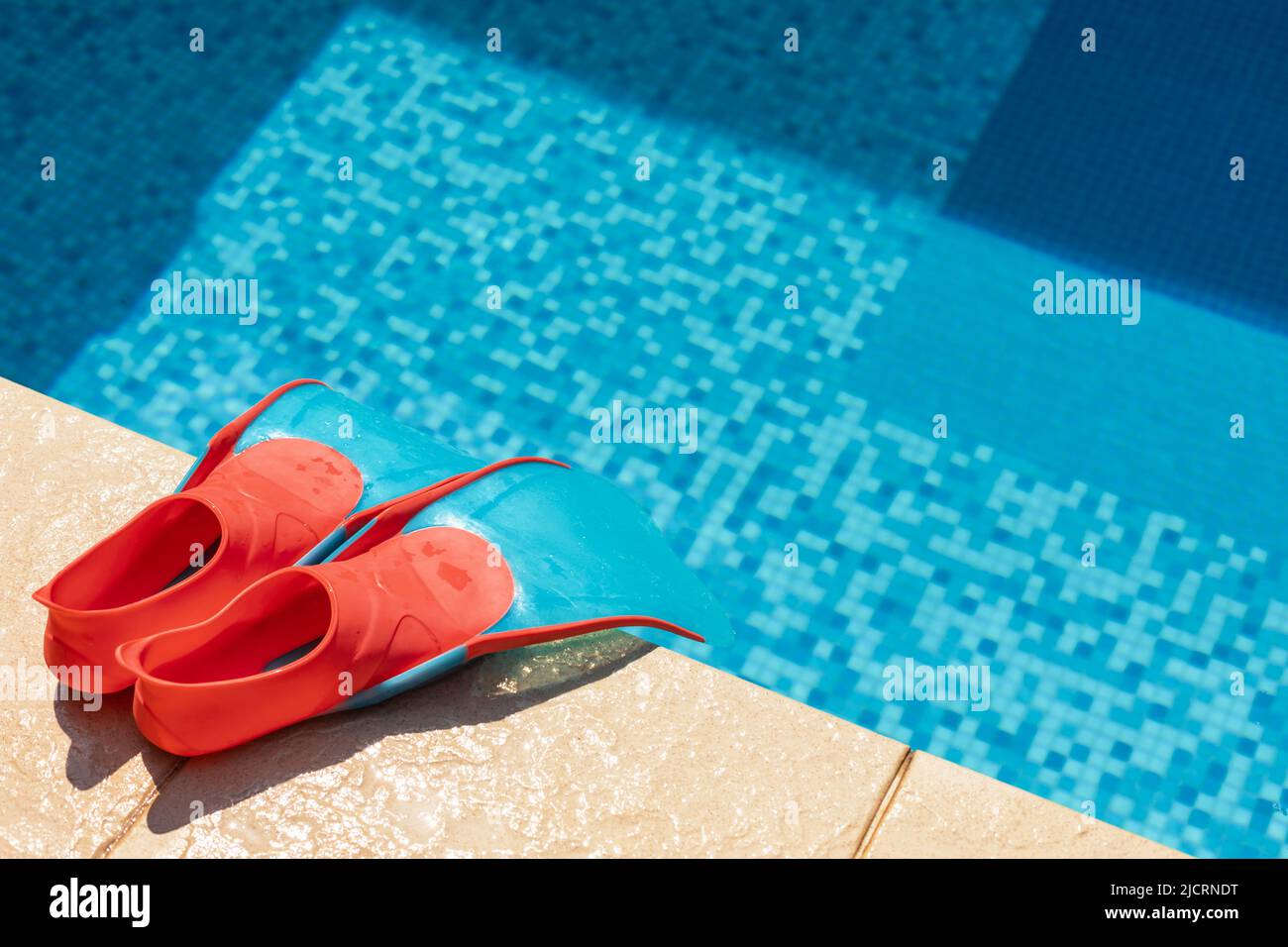 Children's flippers at a swimming pool side - summer water sport activities concept Stock Photo