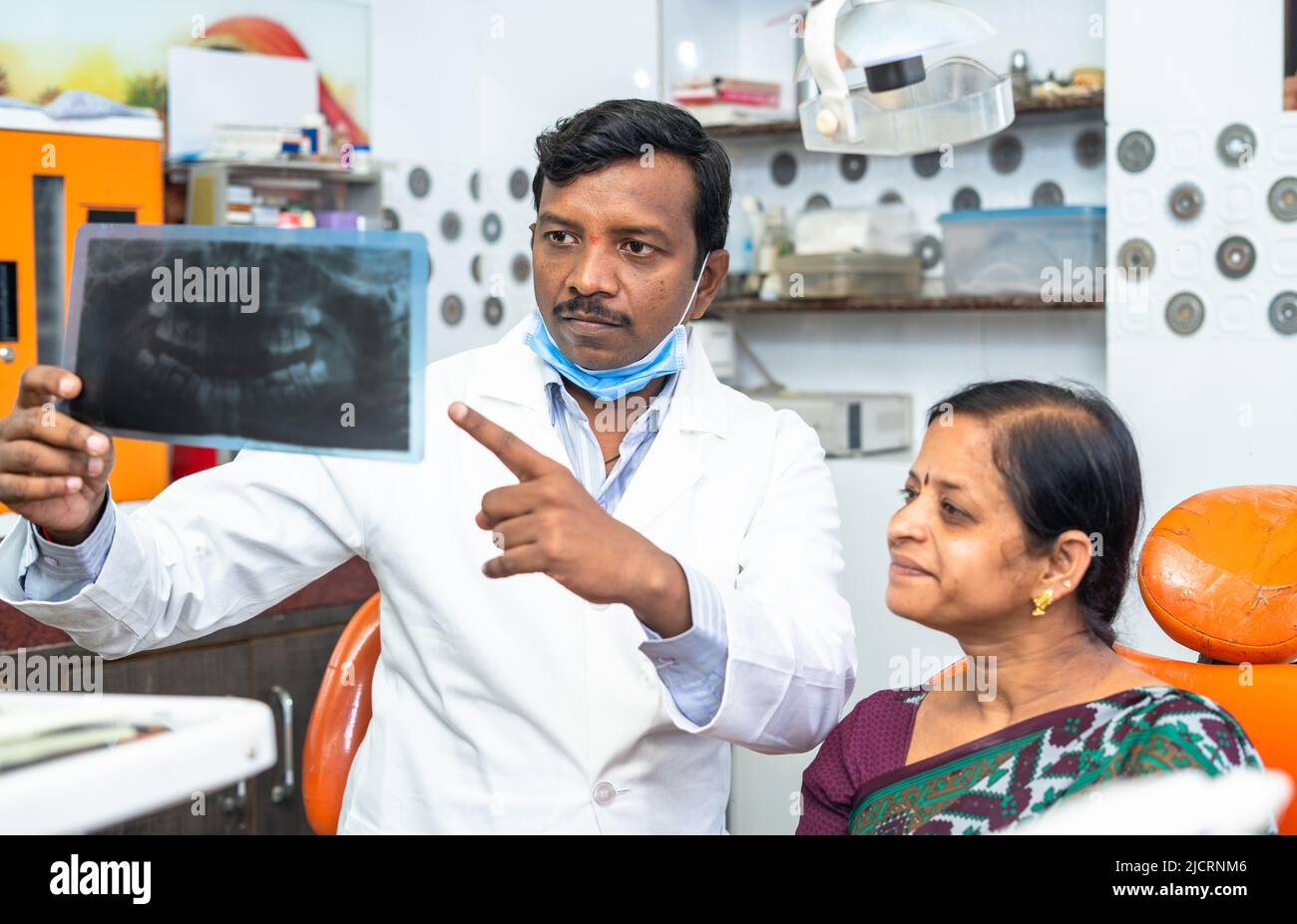 Dentist explaining teeth x-ray report to woman patient at hospital about cavity or dental problems - concept of oral care, expertise and dental care. Stock Photo
